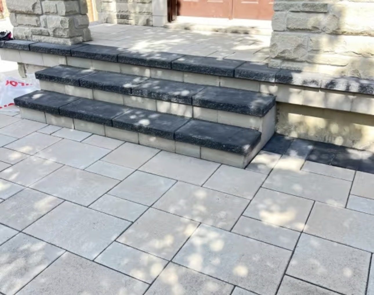 Charcoal-capped front entrance steps over cream-stone risers with a tumbled silver paver landing